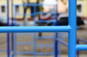 tubos de metal azul e barras transversais contra um campo de esportes de rua para treinamento de atletismo. equipamento de ginástica esportiva ao ar livre. foto macro com foco seletivo e fundo extremamente desfocado