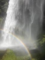 um arco-íris na frente da cachoeira seljalandsfoss na costa sul da islândia em um dia ensolarado foto