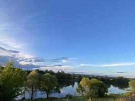 belo pôr do sol no lago. pôr do sol refletido na água - céu azul e laranja com nuvens e árvores em silhueta foto