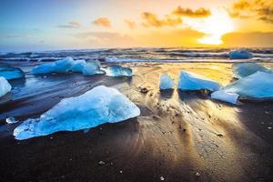 rocha de gelo com praia de areia preta na praia de jokulsarlon, ou praia de diamante, no sudeste da Islândia foto