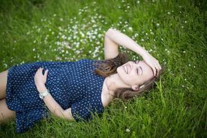 jovem sorridente deitada na grama verde foto