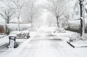 cidade europeia coberta de neve, estrada na rua com árvores e casas particulares foto