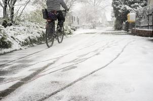 ciclista percorre uma cidade coberta de neve ao longo da rua de uma cidade europeia durante a geada foto