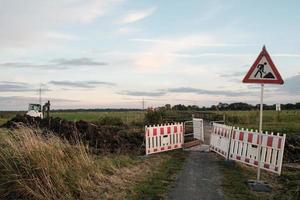 reparação de uma estrada rural, um sinal de aviso, uma cerca e equipamentos especiais foto