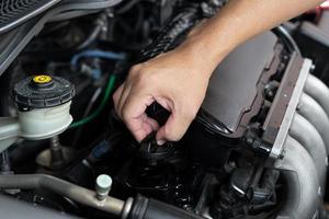 homem técnico de carro usar chave de fenda remover parafuso no conceito de serviço e manutenção da sala de máquinas foto