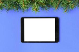 tablet com tela em branco sobre o fundo de cor pastel roxo. vista superior com decoração de natal foto