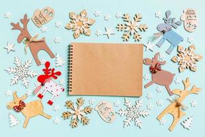 vista superior do notebook sobre fundo azul feito de brinquedos e decorações de férias. conceito de enfeite de natal foto