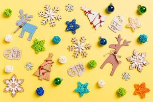 vista superior do fundo amarelo com brinquedos e decorações de ano novo. conceito de tempo de natal foto