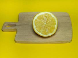 um limão fatiado em uma pequena placa de corte em um fundo amarelo. citrinos na mesa. fundo brilhante. alimentos fortificados saudáveis para uma dieta. foto
