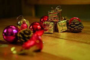 ano novo e decorações temáticas de presente de natal em fundo de madeira, consistindo de uma caixa de presente dourada. bolas coloridas brilhantes pinhas secas e pequenos sinos espaço livre para design foto