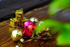 ano novo e decorações temáticas de presente de natal em fundo de madeira, consistindo de uma caixa de presente dourada. bolas coloridas brilhantes pinhas secas e pequenos sinos espaço livre para design foto