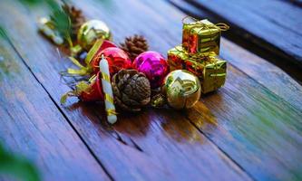 ano novo e decorações temáticas de presente de natal em fundo de madeira, consistindo de uma caixa de presente dourada. bolas coloridas brilhantes pinhas secas e pequenos sinos espaço livre para design foto