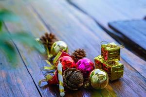 ano novo e decorações temáticas de presente de natal em fundo de madeira, consistindo de uma caixa de presente dourada. bolas coloridas brilhantes pinhas secas e pequenos sinos espaço livre para design foto