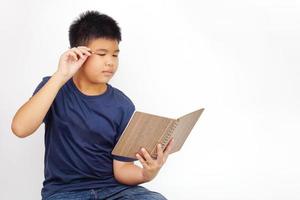 menino sentado leu um livro com um lápis na orelha. conceito de educação e aprendizagem. foto