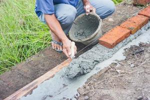 trabalhadores da construção civil instalam tijolos e cimento de fileiras de tijolos nas paredes externas foto