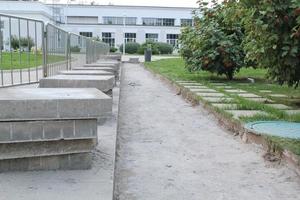 grande pilha de lajes quadradas cinza e meio-fio para trabalho no canteiro de obras na rua da cidade. Repare o pavimento, colocando na passarela a pilha de pedras de pavimentação de concreto. materiais de construção, paralelepípedos foto