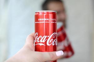 carcóvia. ucrânia - 2 de maio de 2022 jovem feliz levanta lata de coca-cola com amiga no interior da garagem foto