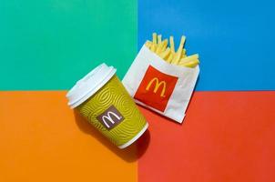 kharkov, ucrânia - 12 de maio de 2022 batatas fritas do mcdonald em pequeno saco de papel e xícara de café em fundo colorido brilhante foto