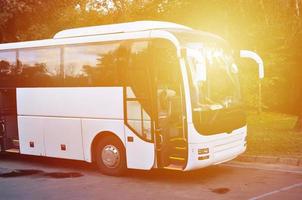 ônibus turístico branco para excursões. o ônibus está estacionado em um estacionamento perto do parque foto