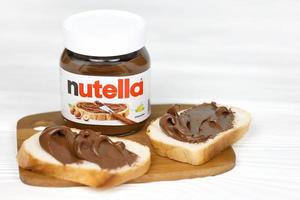 carcóvia. ucrânia - 2 de maio de 2022, lata de vidro de nutella e espalhada em pão recém-assado. nutella é fabricado pela empresa italiana ferrero introduzido pela primeira vez em 1964 foto