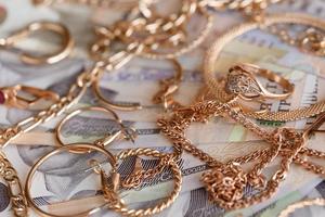 muitos anéis, brincos e colares dourados caros com grande quantidade de notas de dinheiro ucranianas. conceito de loja de penhores ou joalheria. comércio de joias foto