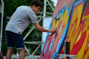 kharkov, ucrânia - 27 de maio de 2022 festival de artes de rua. jovens desenham grafite em paredes de madeira portáteis no centro da cidade. o processo de pintura em paredes com latas de aerossol foto