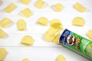 kharkov, ucrânia - 5 de maio de 2022 pringles sabor de cebola creme azedo. tubo de papelão pode com batatas fritas pringles na mesa branca. pringles é uma marca de salgadinhos de propriedade da empresa Kellogg foto