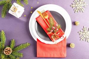 belo design moderno do natal servindo da mesa festiva. guardanapos vermelhos dobrados em leque com decorações em pratos brancos e escuros. foto