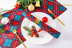 serviço festivo da mesa de ano novo. guardanapos nas cores tradicionais do ano novo e natal em uma mesa branca com garfo e faca de ouro. foto
