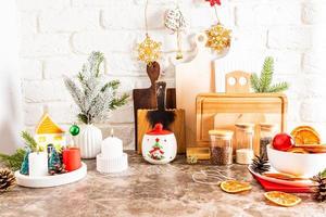 bela vista da bancada da cozinha decorada para o ano novo e natal. velas acesas, galho em um vaso, fatias de laranja seca.