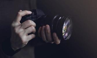 mulher jovem fotógrafo usando a câmera para tirar foto. tom escuro. foco seletivo na mão foto