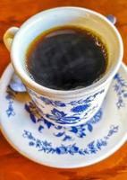 pote de xícara branca azul com mesa de madeira de café preto méxico. foto