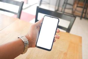 mão de jovem usando telefone inteligente com tela verde no café foto