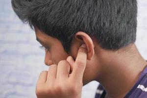 adolescente com dor de ouvido tocando sua orelha dolorosa, foto