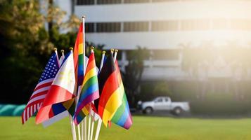 bandeiras de arco-íris e bandeiras de muitos países em frente ao gramado verde da escola asiática, conceito para celebração dos gêneros lgbtq no mês do orgulho em todo o mundo, foco suave e seletivo. foto