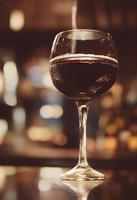 copo de vinho tinto escuro em um pub em uma superfície reflexiva foto