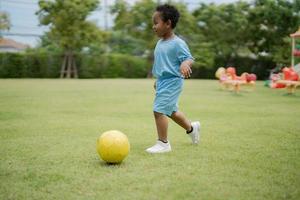 menino bonitinho com bola de futebol no parque em um dia ensolarado. foto