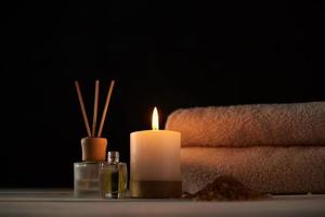 toalhas, vela e óleo de massagem na mesa branca foto