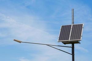 luz da cidade pública com painel solar alimentado no céu azul com nuvens foto