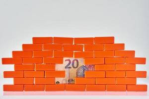 parede de tijolo quebrada com uma nota de euro no buraco. conceito de negócios e finanças foto