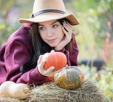 jovem feliz com abóbora no jardim de outono foto