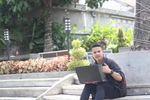 atraente jovem asiático usando laptop no espaço de coworking com cara de feliz foto