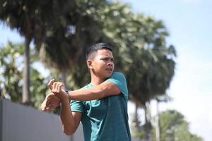 jovem rapaz asiático aquecendo para correr de manhã foto