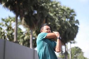 jovem rapaz asiático aquecendo para correr de manhã foto