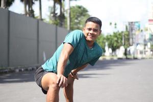 jovem rapaz asiático aquecendo para correr de manhã foto