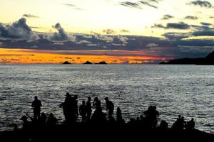 rio de janeiro, rj, brasil, 2022 - pessoas em silhueta assistem o pôr do sol na rocha do arpoador, praia de ipanema foto