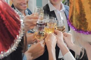 close-up mãos de pessoas de negócios tilintando copos de vinho na festa de ano novo do escritório com sentimento de prazer. foto