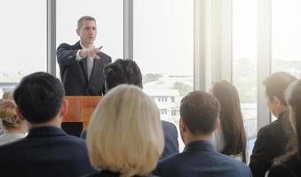 orador público masculino sênior dando discurso ao público em evento de seminário corporativo na sala de conferências com efeito de luz. foco seletivo. foto