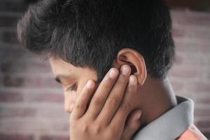 adolescente com dor de ouvido tocando sua orelha dolorosa, foto