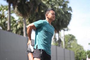 jovem rapaz asiático aquecendo para correr de manhã foto